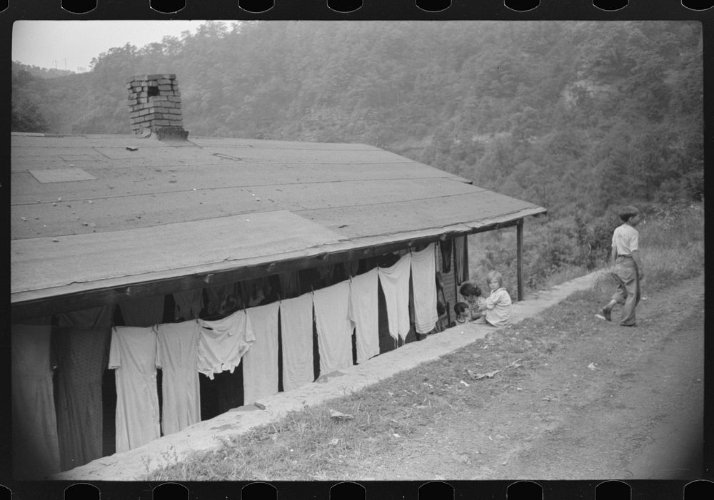 Front of house in abandoned mining community. In foreground is part of main county road. Marine, West Virginia. Sourced from…