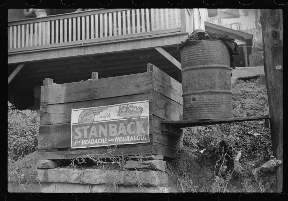 Coalbox in front of miner's house with typical patent medicine advertisement on it. Caples, West Virginia. Sourced from the…