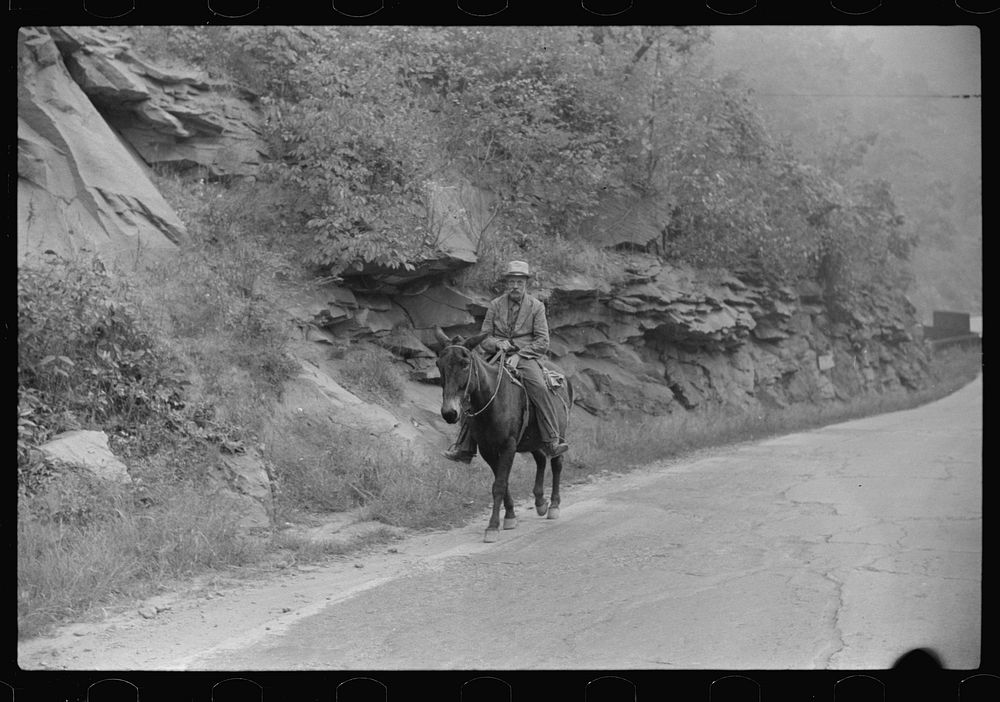 Old miner on donkey, still quite a common means of transportation, in county road near Mohegan, West Virginia. Sourced from…