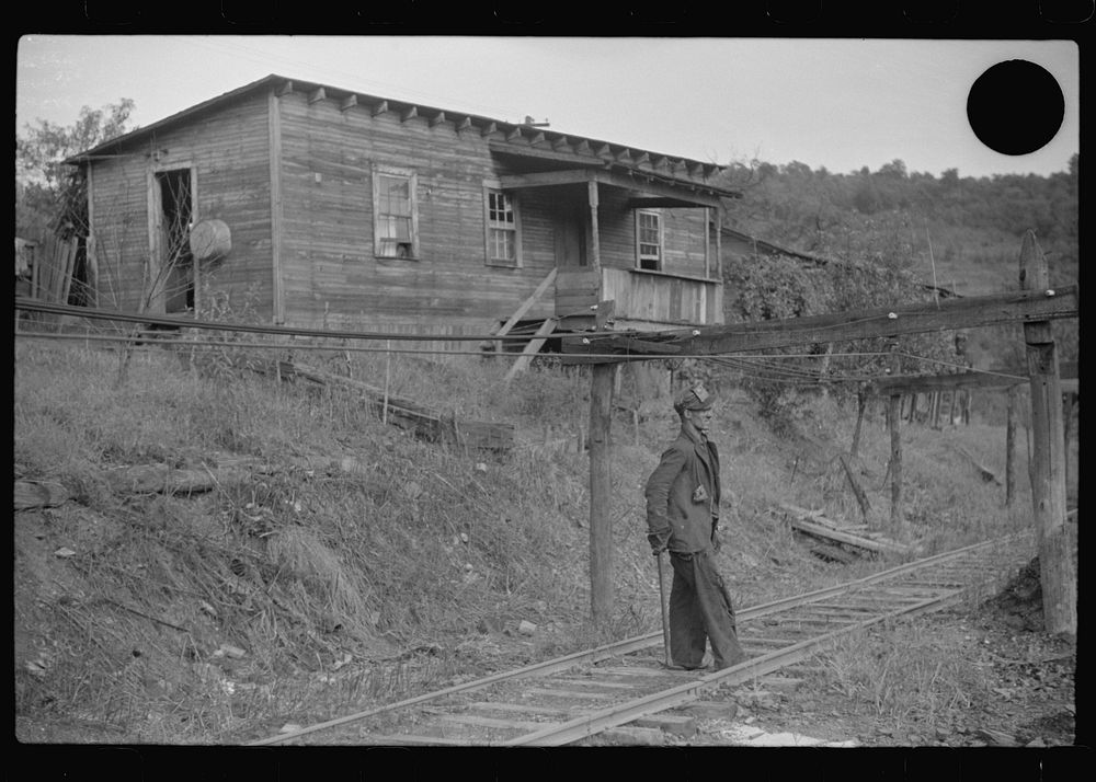[Untitled photo, possibly related to: Coal miner returning from work with pick over shoulder. The "Patch," Chaplin, West…