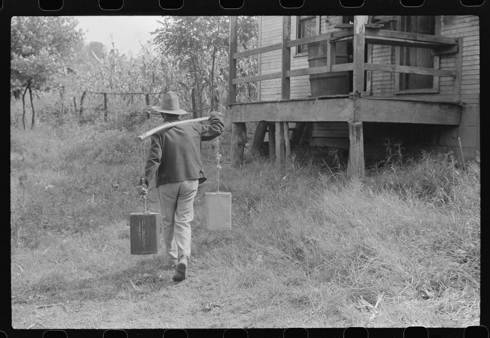 Mexican miner carrying water the way he learned as a boy, from about two miles downhill. Bertha Hill, West Virginia. Sourced…