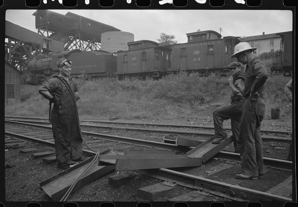 [Untitled photo, possibly related to: Workman cutting a steel beam with an acetylane torch near mine tipple and engine…