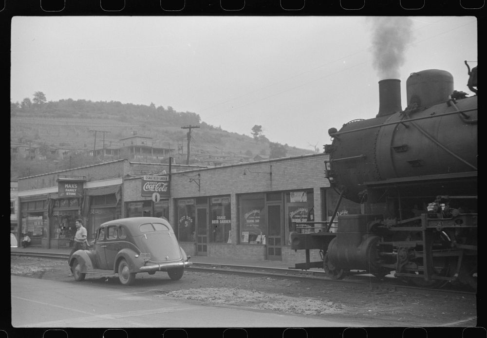 [Untitled photo, possibly related to: Train pulls coal through center of town past miners' homes (company houses) several…