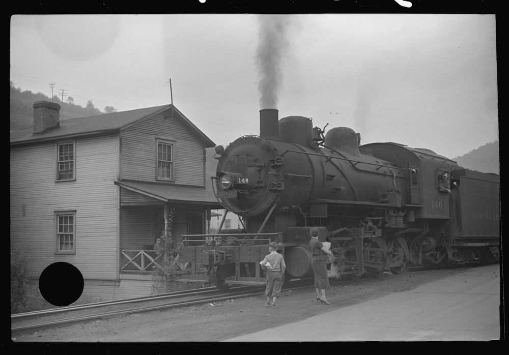 [Untitled photo, possibly related to: Train pulls coal through center of town past miners' homes (company houses) several…