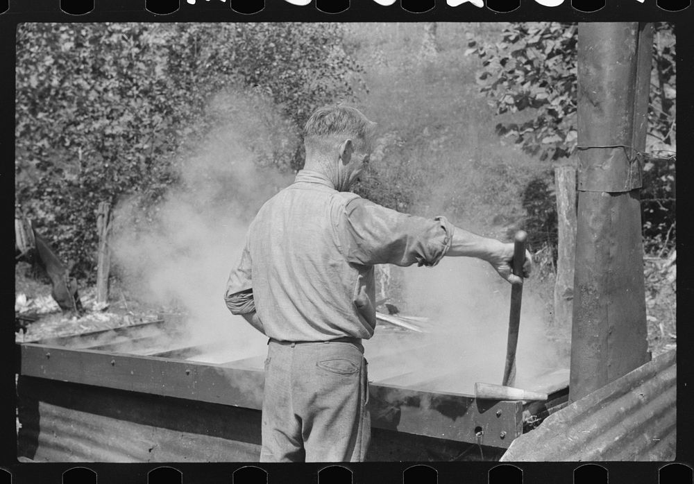 Farmer stirring sorghum molasses which is being cooked in vat. Racine, West Virginia. Sourced from the Library of Congress.
