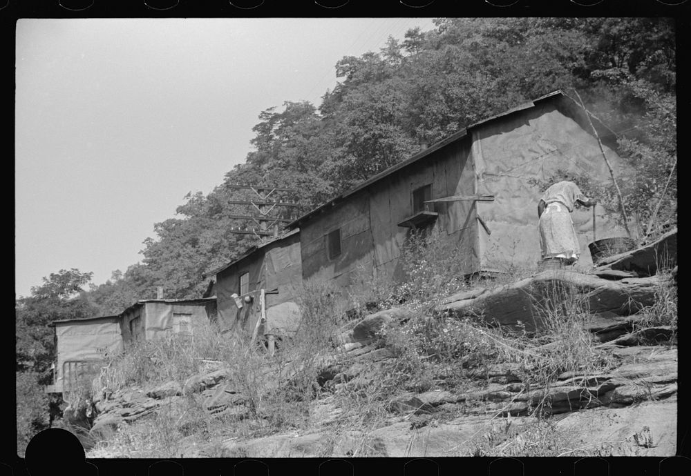 [Untitled photo, possibly related to:  woman washing clothes outside of shacks along the river. On highway between…