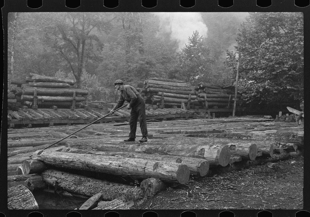 [Untitled photo, possibly related to: Men spiking logs to go up ramp into sawmill. It was working only halftime and was even…