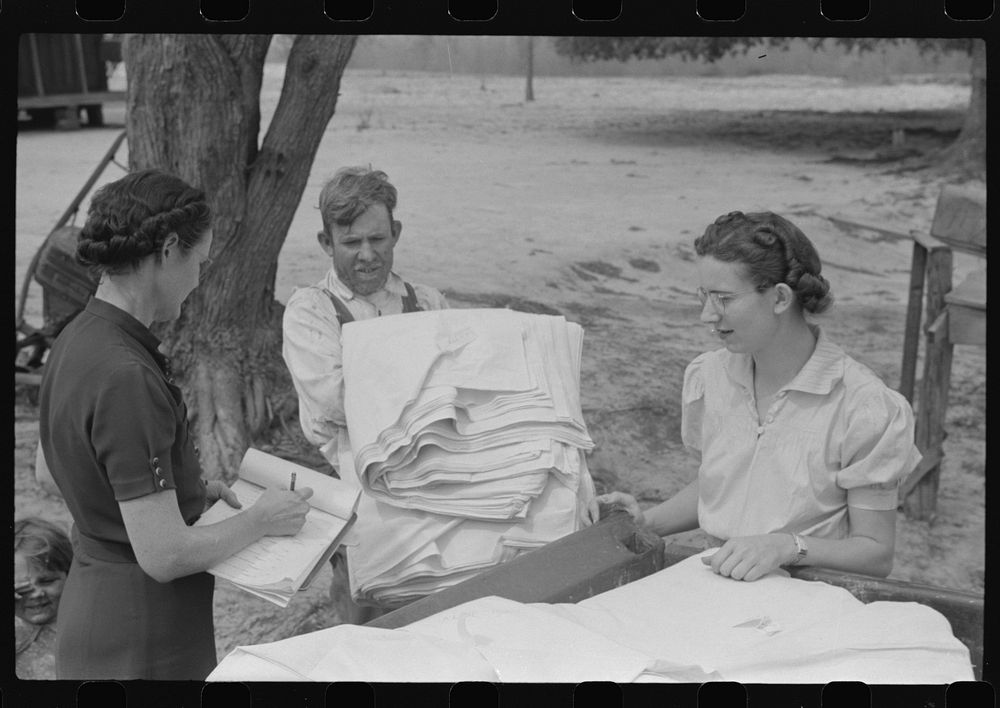 Miss Hesterley and Miss Christian, FSA (Farm Security Administration) home economists, delivering sheeting to Mr. Adkins…