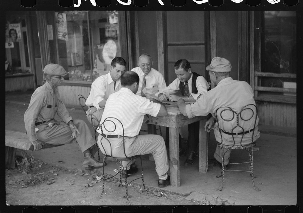 Playing dominoes or cards in front of drug store in center of town, in Mississippi Delta, Mississippi. Sourced from the…