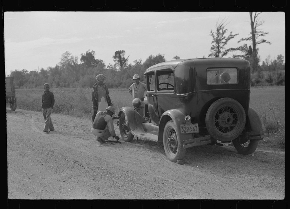 [Untitled photo, possibly related to: Repairing tire on road near Knowlton Plantation, Perthshire, Mississippi Delta…