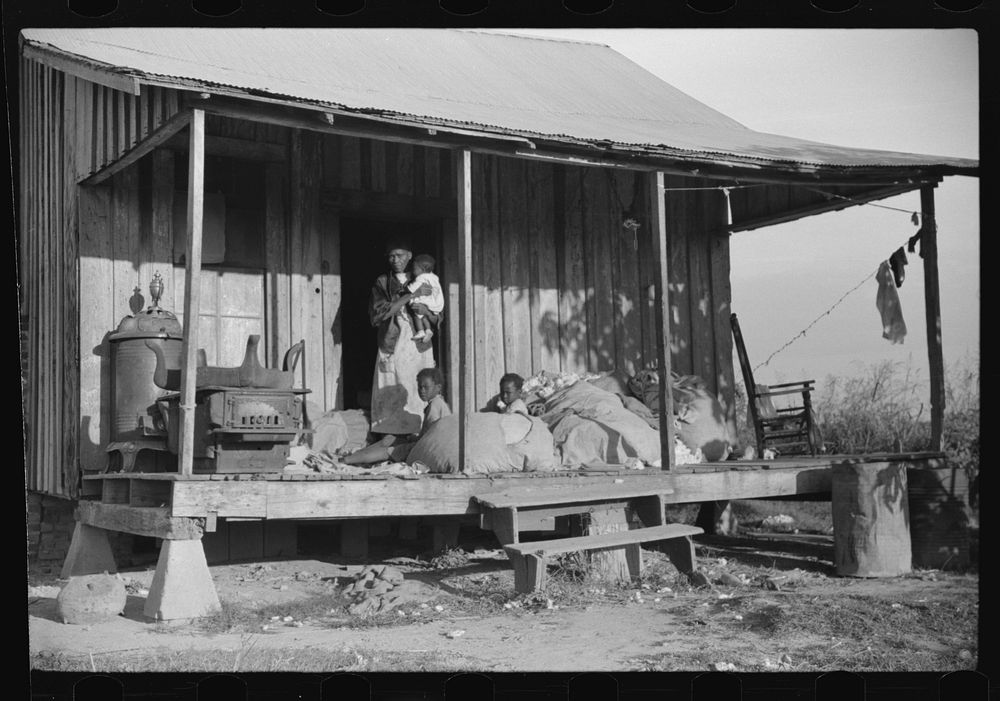 Home of  wagehand, Knowlton Plantation, Perthshire. On the porch are sacks of cotton. Mississippi, Delta Mississippi.…