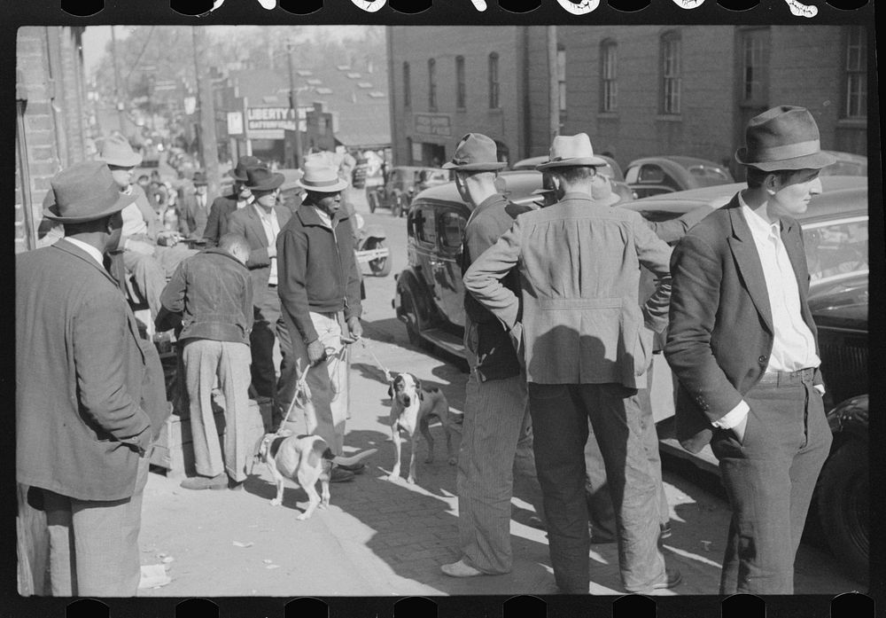 [Untitled photo, possibly related to: Farmer selling hound dogs outside tobacco warehouse during auction sales, Durham…