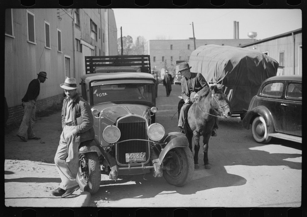 [Untitled photo, possibly related to: Discussion between farmers waiting outside warehouse during auction sales of tobacco.…