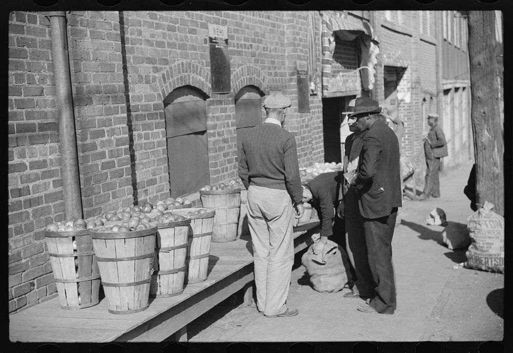 [Untitled photo, possibly related to: Farmer having corn removed from his foot on street outside tobacco warehouse during…