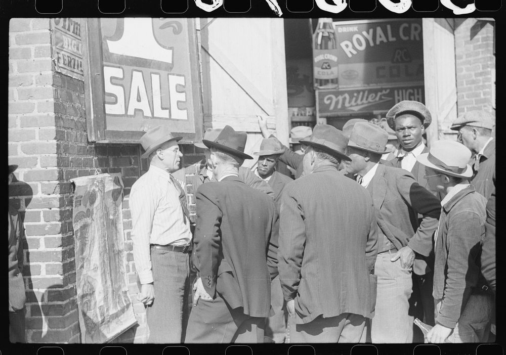 Patent medicine salesman talking to farmers outside warehouse during tobacco auction sales. Durham, North Carolina. Sourced…