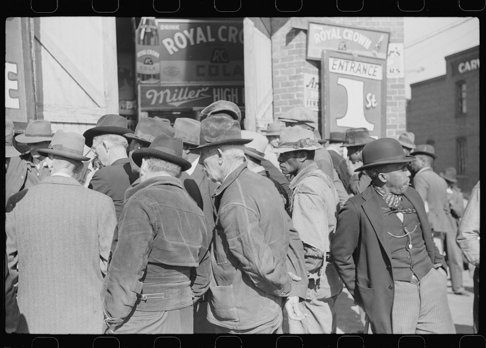 Spectators listening to patent medicine salesman who has his stand outside tobacco warehouse during tobacco auction sales.…
