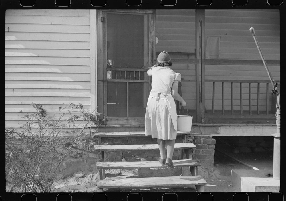One of the Wilkins clan going into house with water. Tally Ho, near Stem, Granville County, North Carolina. Sourced from the…