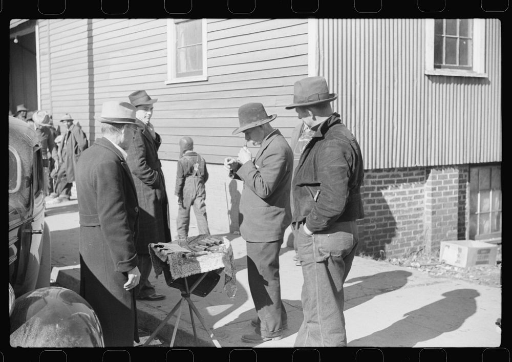 Salesman displaying patent medicine to farmers who have brought tobacco to warehouse and are waiting outside for the sales…