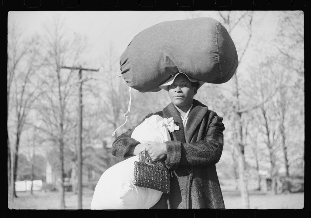 [Untitled photo, possibly related to: Woman carrying laundry home along highway between Durham and Mebane, North Carolina]…