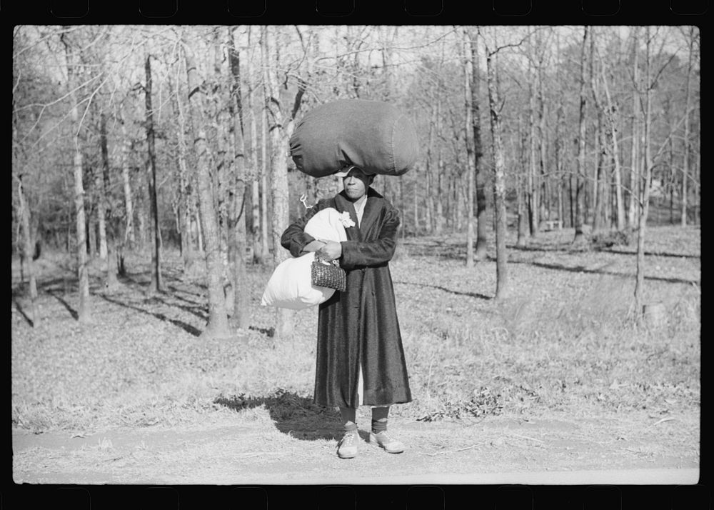 [Untitled photo, possibly related to: Woman carrying laundry home along highway between Durham and Mebane, North Carolina]…