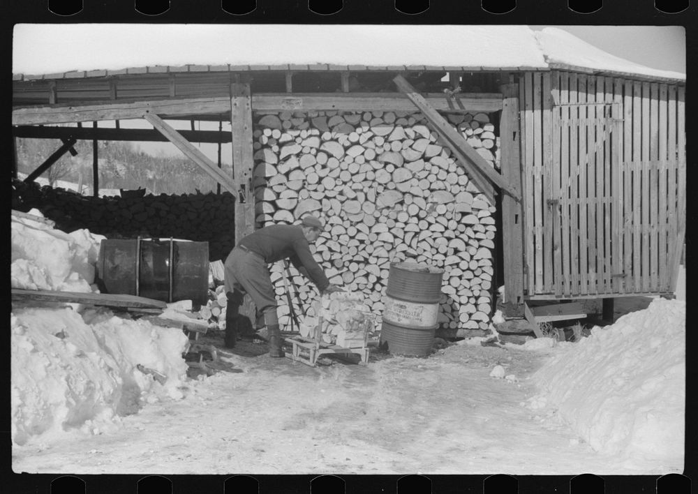 Hired hand on Mr. Dickinson's farm in Lisbon, near Franconia, New Hampshire, putting split logs in woodshed for winter fuel.…