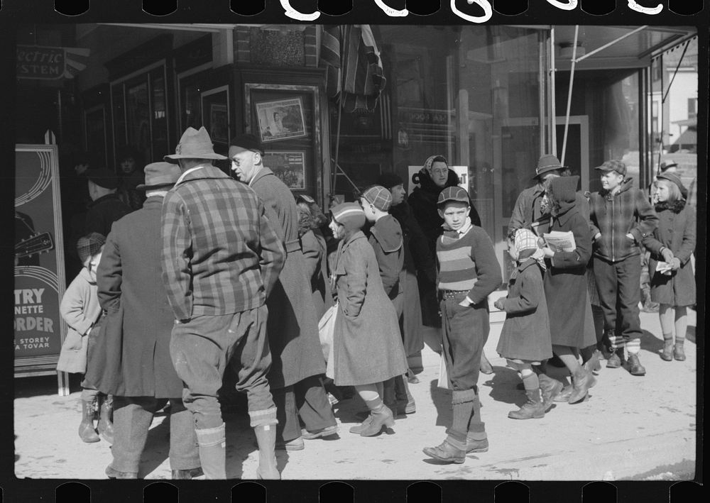 Children and farmers waiting to go into movie on Saturday afternoon, Littleton, New Hampshire. Sourced from the Library of…