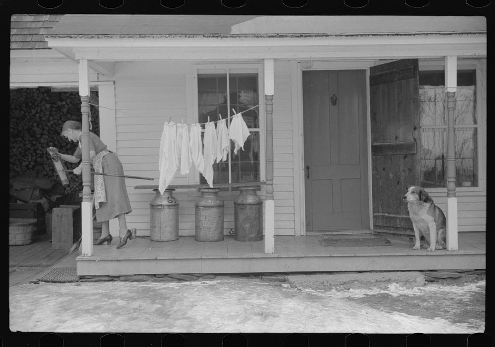 Farmer's wife cleaning brush on front porch of their home, Lisbon, near Franconia, New Hampshire. Sourced from the Library…