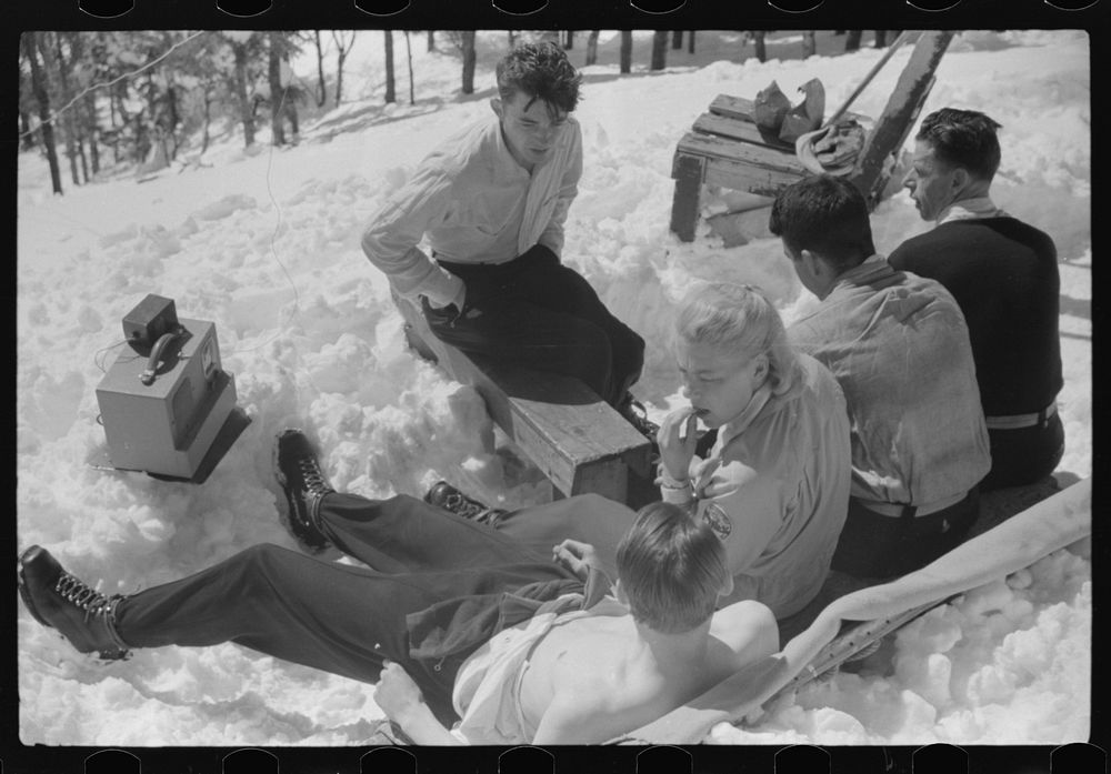 [Untitled photo, possibly related to: Skiers relaxing in the sun during noon hour outside of forest ranger's hut near the…