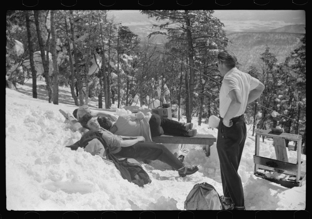 [Untitled photo, possibly related to: Skiers relaxing in the sun during noon hour outside of forest ranger's hut near the…
