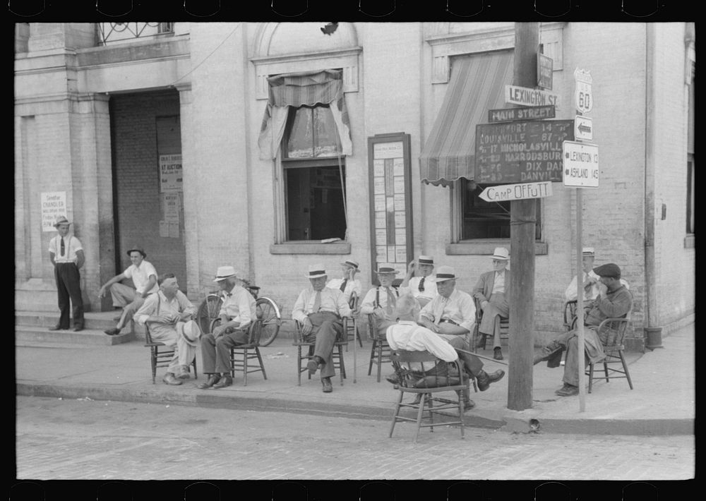 Farmers exchange news and greetings in front of courthouse on Saturday. Versailles, Kentucky. Sourced from the Library of…