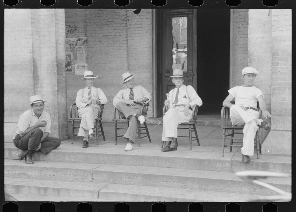 Farmers exchange news and greetings in front of courthouse on Saturday afternoon. Versailles, Kentucky. Sourced from the…