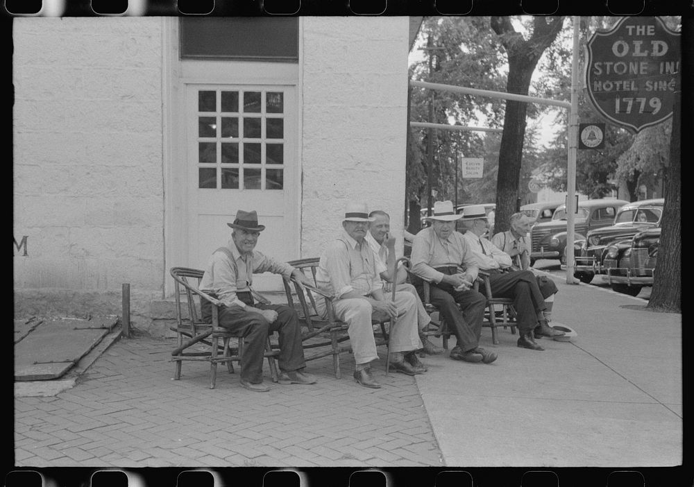 Townspeople visiting while sitting in front of Old Talbott Tavern on Saturday afternoon. Bardstown, Kentucky. Sourced from…