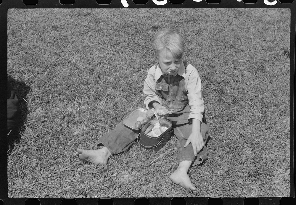 Child eating lunch during the noon hour at school in Breathitt County, Kentucky. In his lunch pail were cold potatoes, corn…