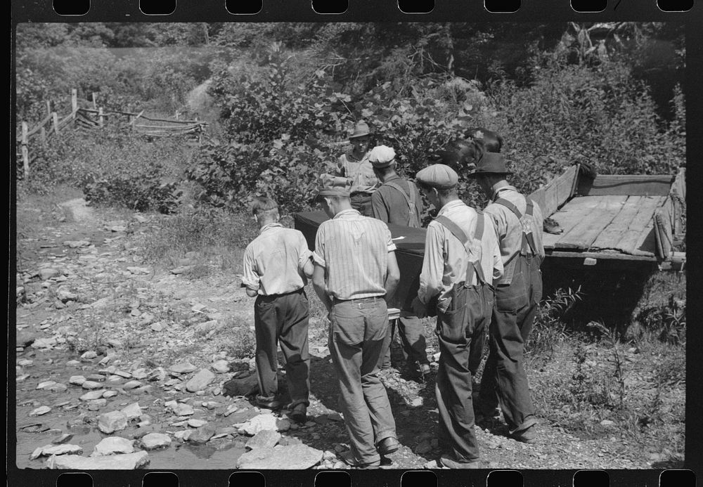 Mountain people carrying a homemade coffin up creek bed to the family plot on the hillside where it will be buried. This…