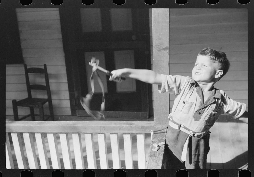 Mountain child shooting slingshot from porch of his home. Near Buckhorn, Kentucky by Marion Post Wolcott