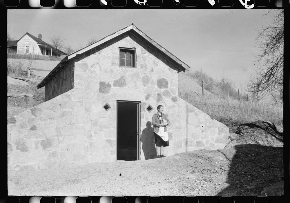 Mrs. S. Castle or Mrs. William S. Allen with canned goods in front of new storage house her husband built on their farm with…