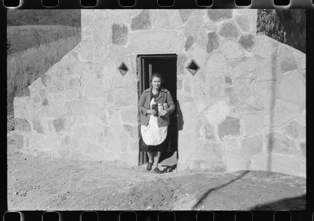 [Untitled photo, possibly related to: Mrs. S. Castle or Mrs. William S. Allen with canned goods in front of new storage…