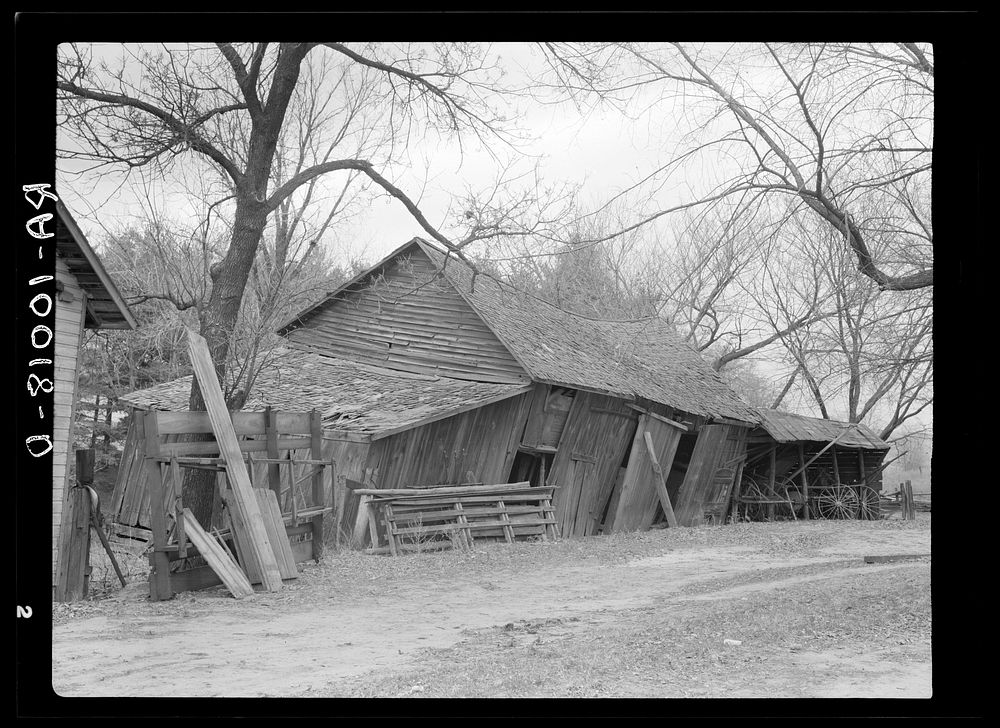 Tool and machine shed on W.H. Cox farm, Clearcreek Township, Johnson County, Iowa. Note how the buildings are propped up.…