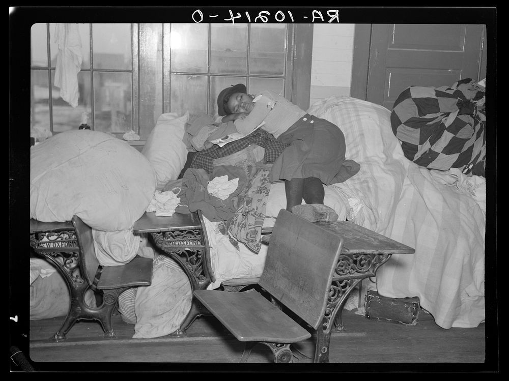 A young flood refugee sleeping amid salvaged household goods in a schoolhouse at Sikeston, Missouri by Russell Lee