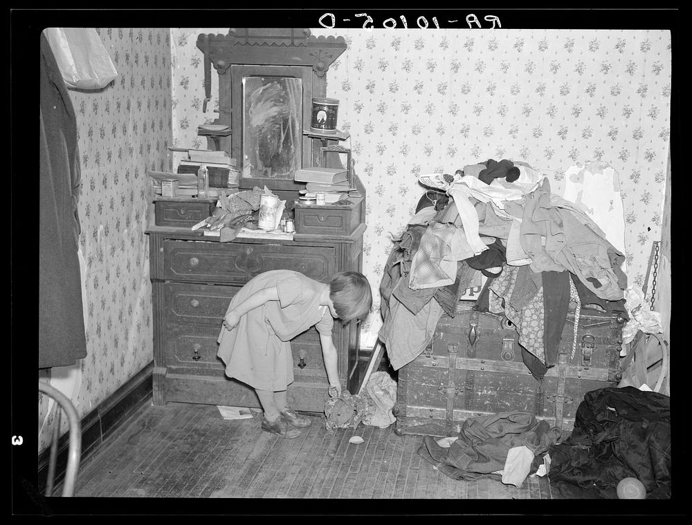 Corner of a bedroom on Edgar Allen farm near Milford, Iowa. There are piles of clothes and rags all over the house. An…
