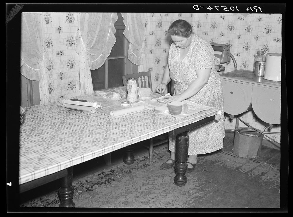 7 a.m. Mrs. Tip Estes, wife of a hired man near Fowler, Indiana, preparing lunches for the five of her nine children who go…