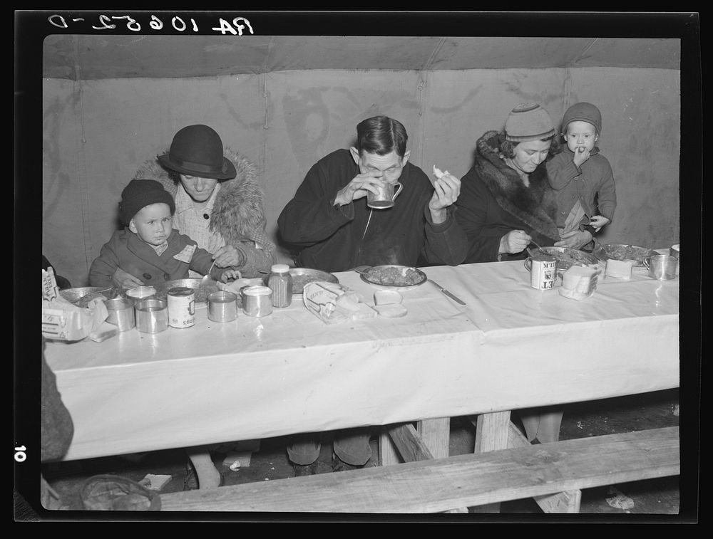 People quartered at Tent City, near Shawneetown, Illinois, eat in large tents from long wooden tables by Russell Lee