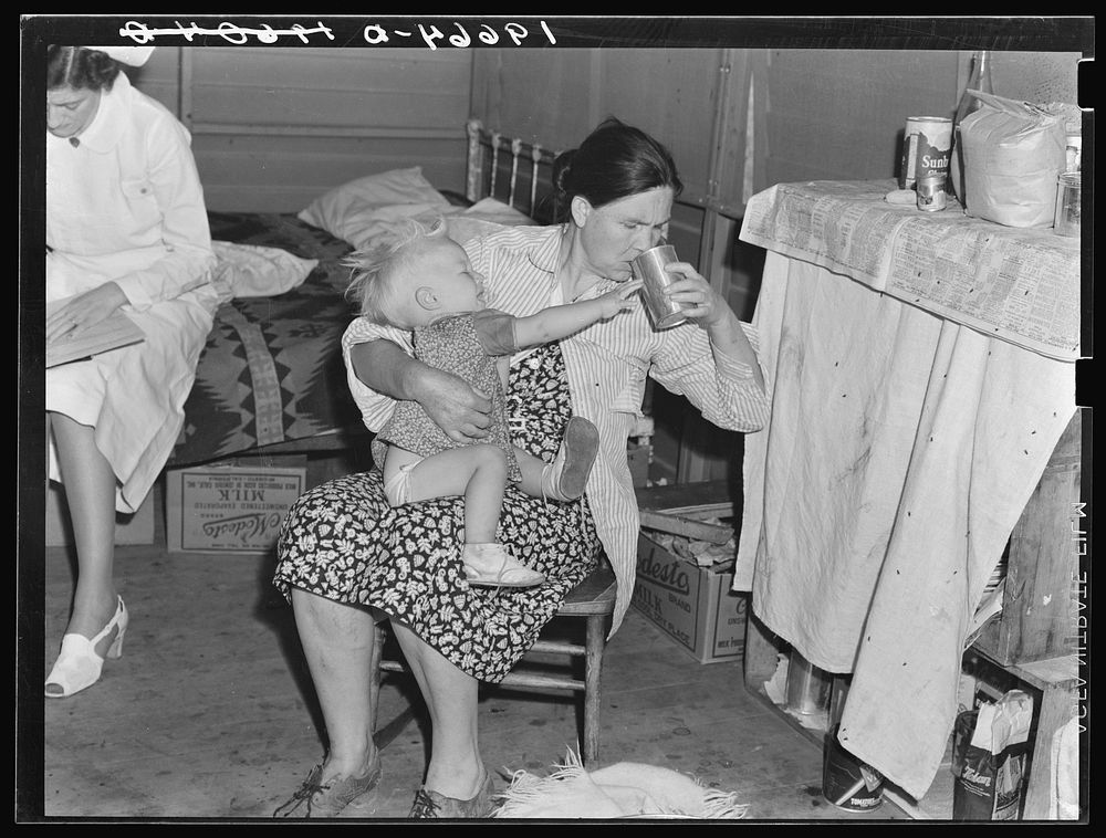 Tulare County, California. In Farm Security Administration (FSA) camp. Mother from Oklahoma tends baby with dysentery and…