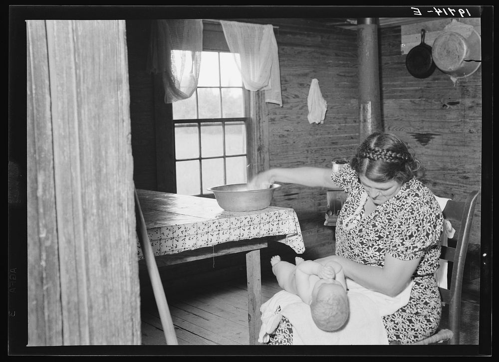 Wife of tobacco sharecropper bathing her baby in kitchen. Person County, North Carolina by Dorothea Lange
