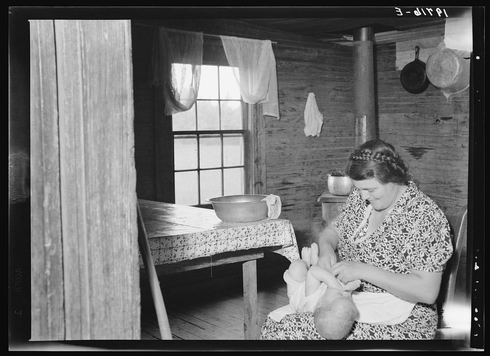 Wife of tobacco sharecropper bathing baby in kitchen. Person County, North Carolina. Sourced from the Library of Congress.