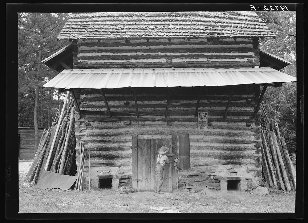 Tobacco barn. Person County, North Carolina. Piece of sheet iron on the left is used to cover the opening of the furnace…