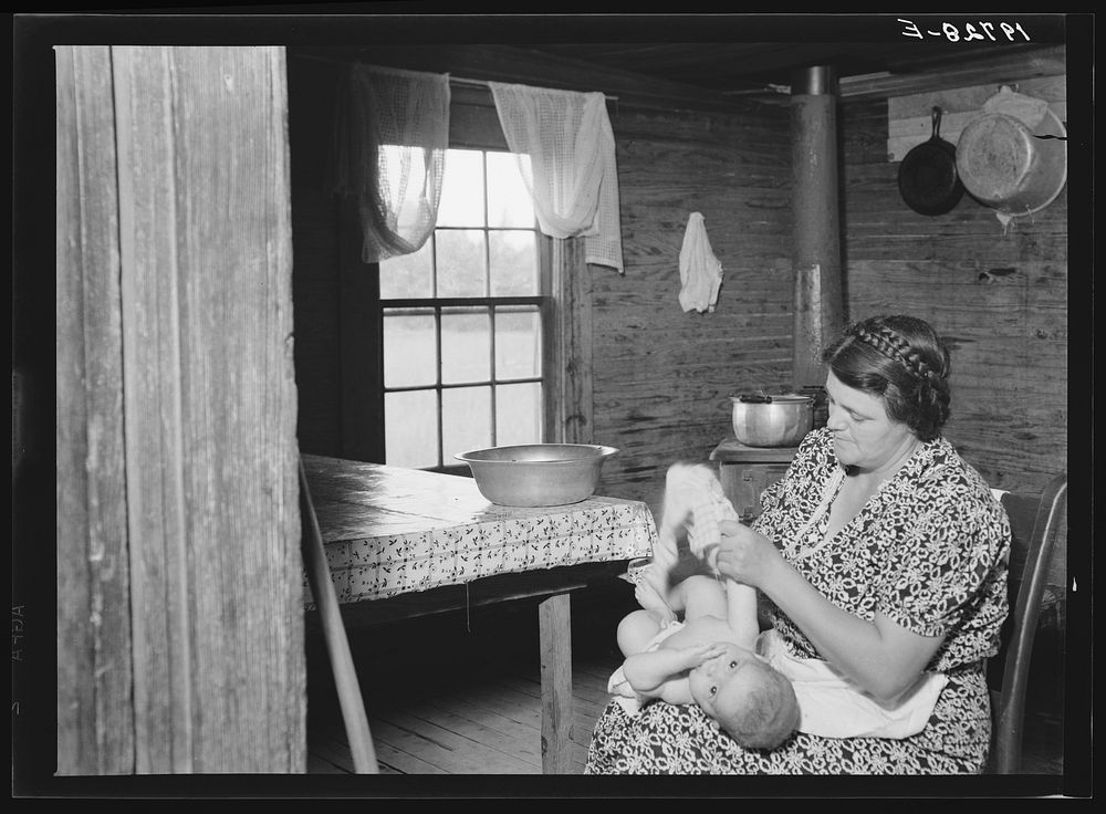 [Untitled photo, possibly related to: Wife of tobacco sharecropper bathing her baby in kitchen. Person County, North…
