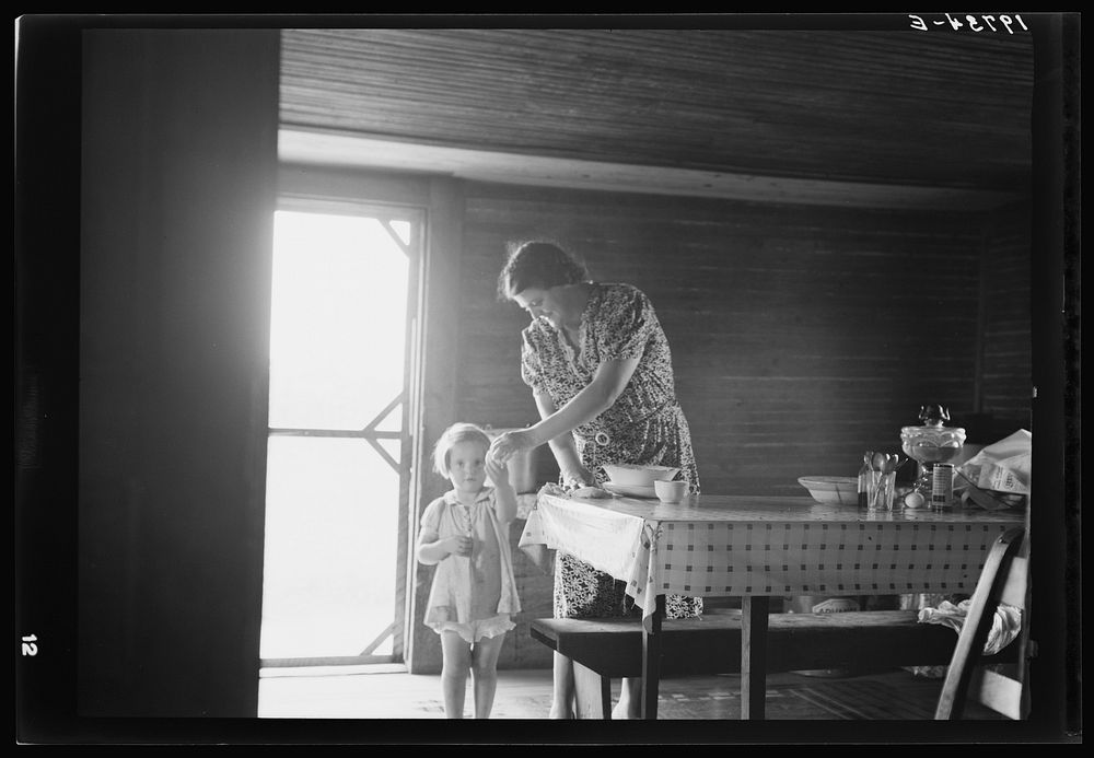 Wife and child of tobacco sharecropper. The littlest girl comes in from outside for something to eat while mother is doing…