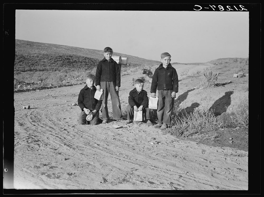 Boys wait for school bus in the morning. Malheur County, Oregon. General caption number 67-1V. Sourced from the Library of…