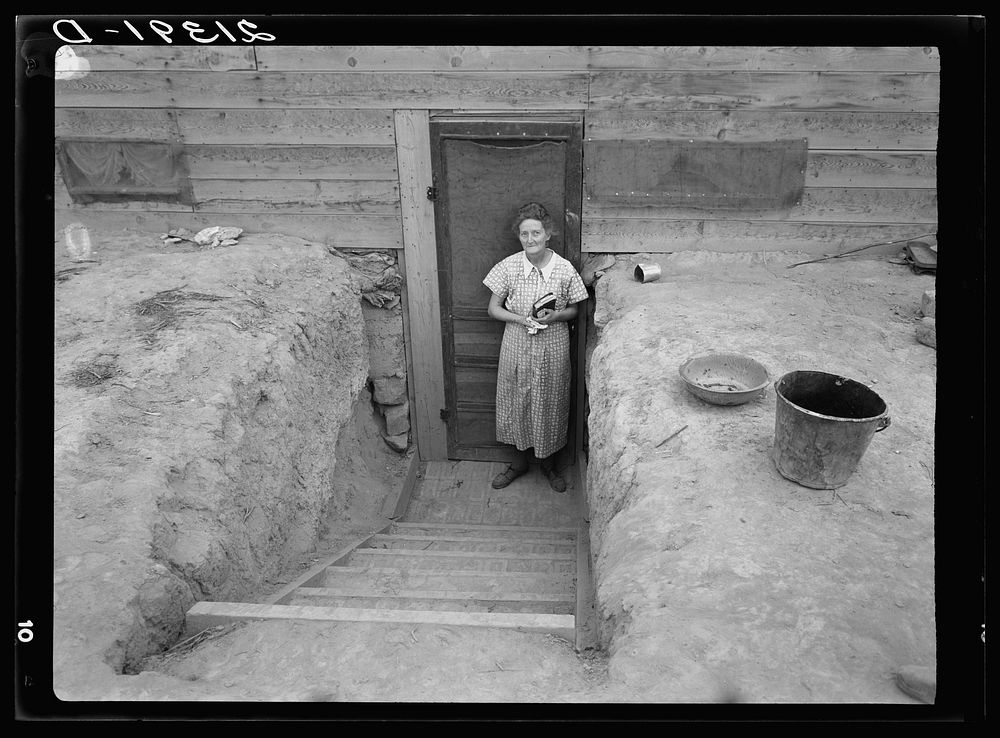 Mrs. Free in doorway of her basement dugout home. Dead Ox Flat, Malheur County, Oregon. Sourced from the Library of Congress.